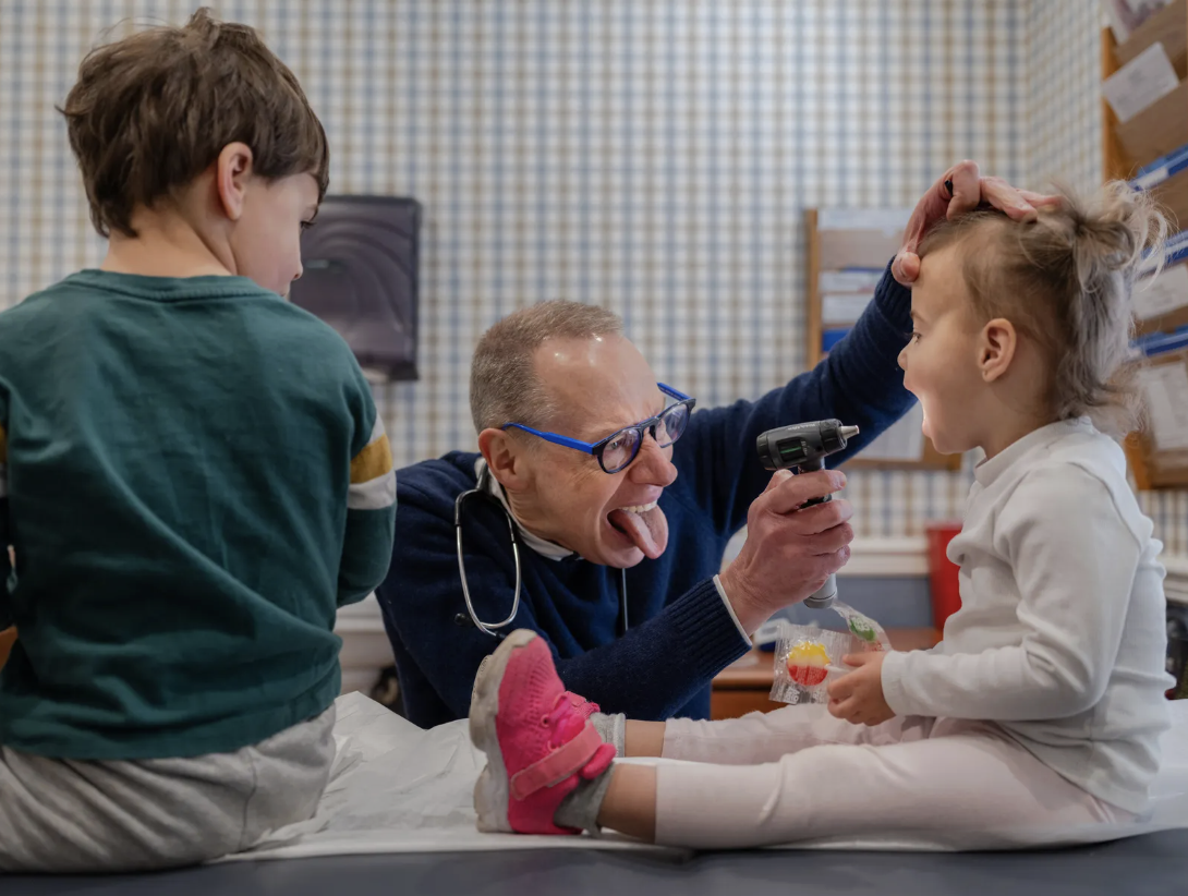 Doctor examines a kid in his office.