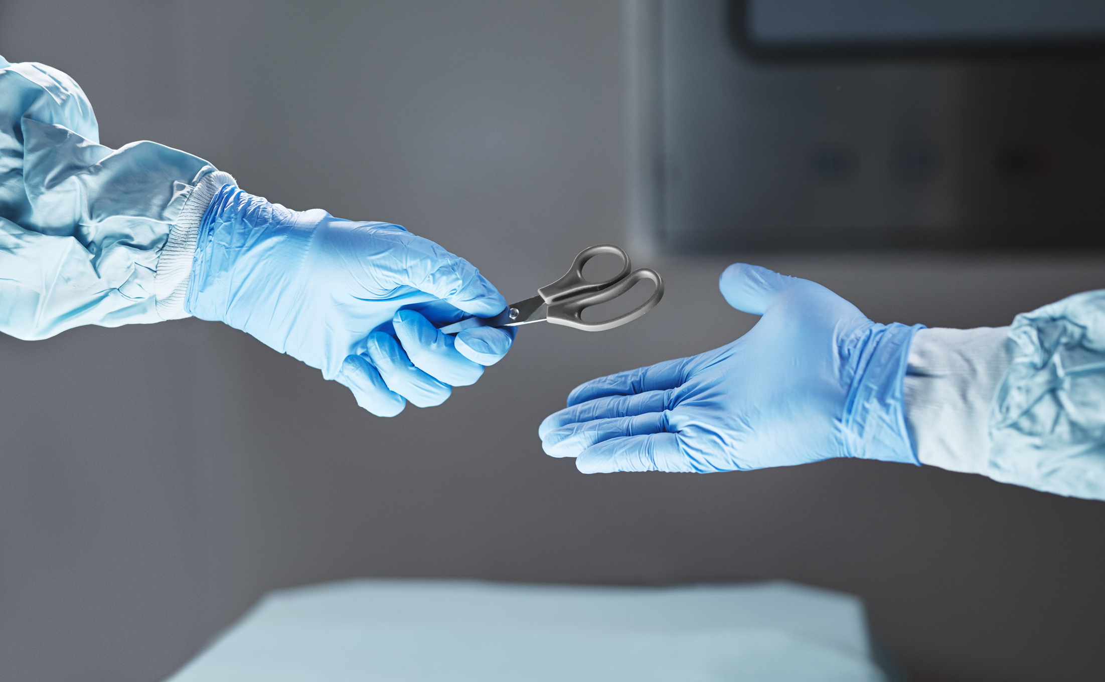 Cropped shot of an unrecognizable surgeon passing his colleague a pair of scissors