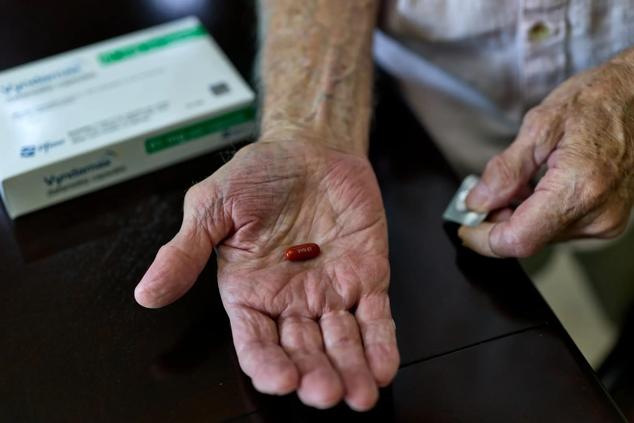 man holds a pill in his open palm