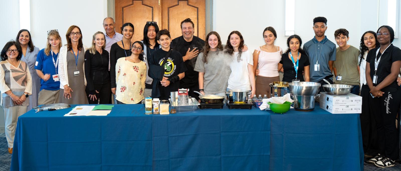 Chef Rocco stands with students behind demo table