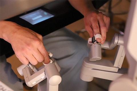 Photograph showing surgeons hands controlling the robotic machine.