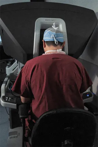 Photograph of surgeon seated at a Davinci robotic surgical system performing a minimally invasive operation.