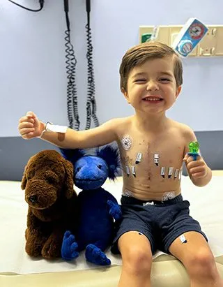 Teddy sits with his stuffed animals after surgery