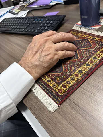 Close up photo of Dr. Raza's hand guiding the mouse of his computer. The mouse pad looks like an ornate middle eastern rug.