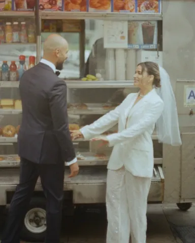 eileen and husband stand in front of food cart on wedding day