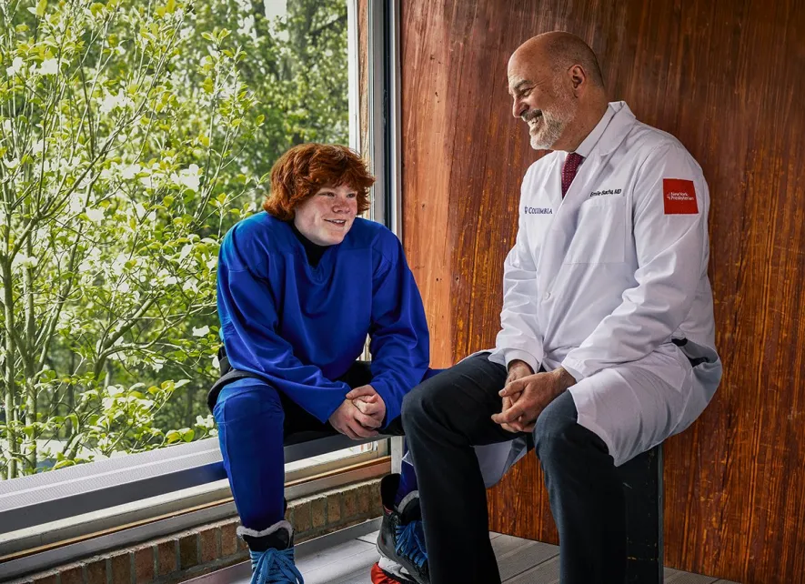 Dr. Bacha sits with his young patient in a window