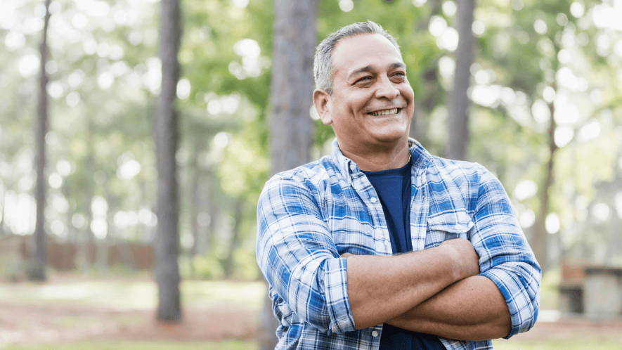 Photo of man outside surrounded by trees smiling