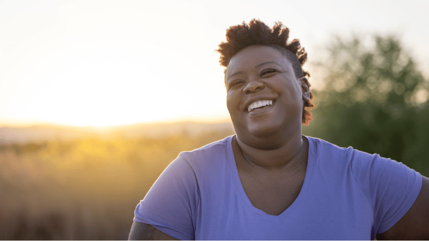 Photo of woman smiling outside with the sun behind her