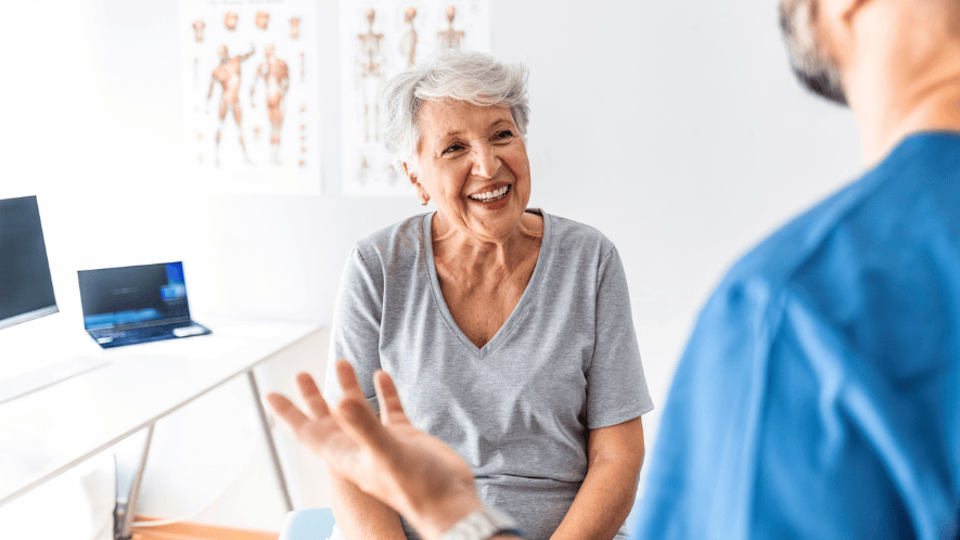 Photo of patient smiling seated looking at doctor speaking