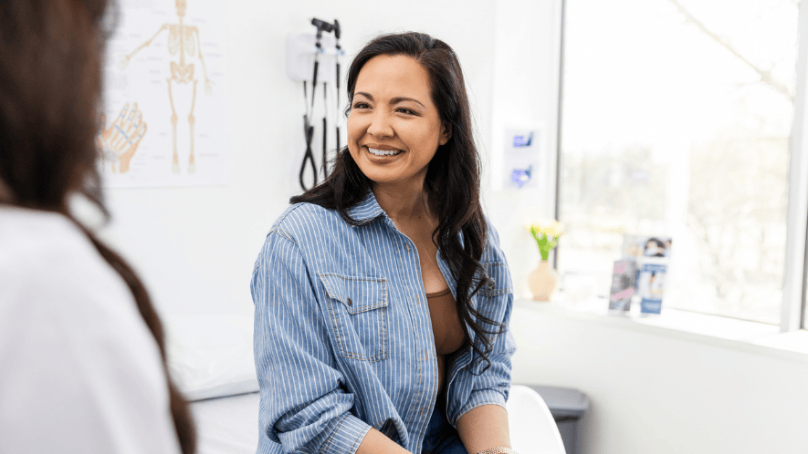 Photo of a patient in a doctors office smiling at the doctor