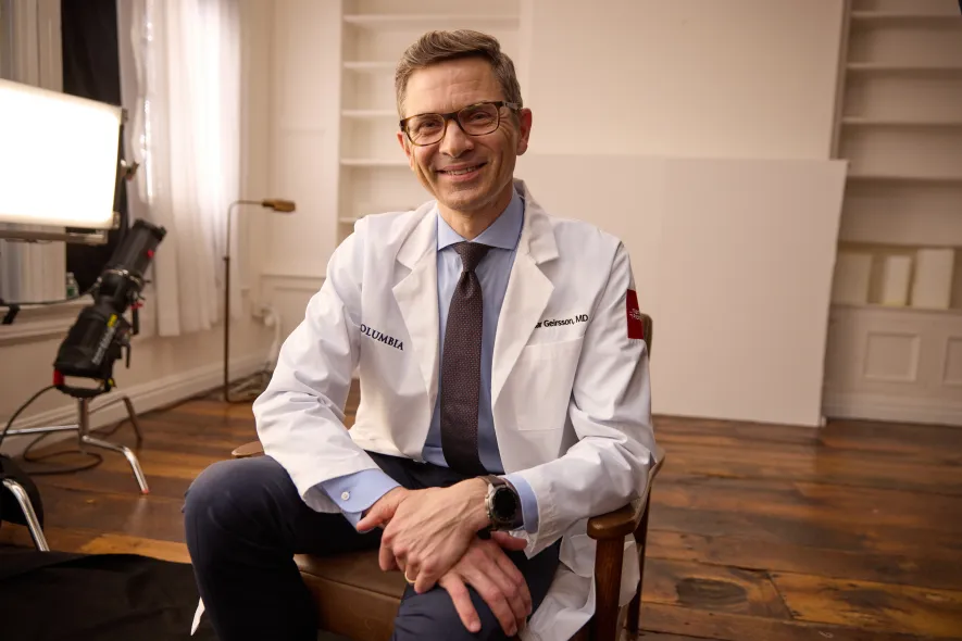 Candid shot of Dr. Arnar Geirsson, in white coat, sitting during a photo shoot
