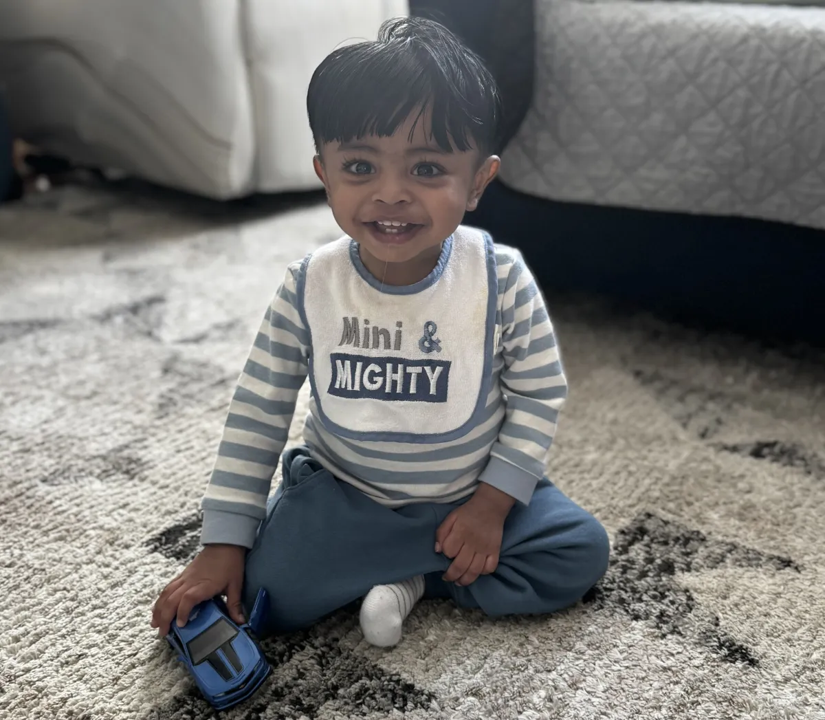 eric, a toddler, sits with a big smile