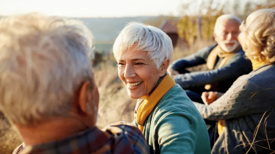 Photo of woman smiling with friends sitting outside in the sun