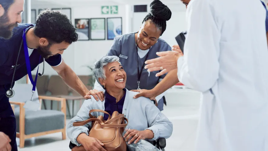 Photo of female patient smiling as a care provider pushes her in her wheelchair