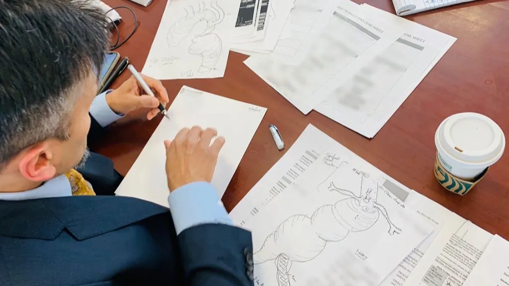 Dr. Virendra Patel sitting at his desk sketching aortas before surgery.